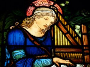 A stained glass depicting a woman playing the harp.