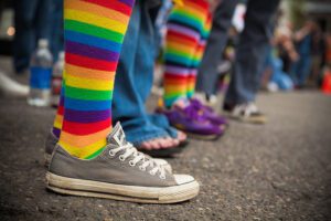 A group of people wearing rainbow colored socks and converse shoes.