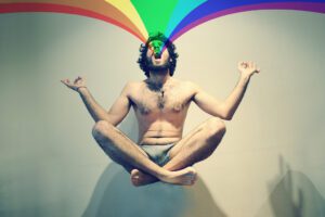 A man meditating with a rainbow over his head.