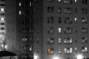 A black and white photo of an apartment building at night.