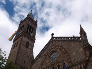 An old church with a rainbow flag on top.