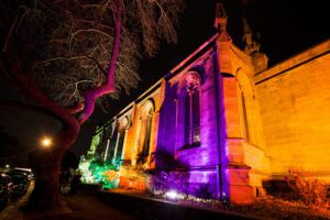 A church lit up at night with colorful lights.