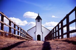 A white church with a fence in the background.