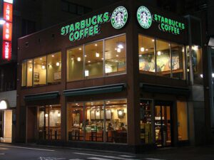 A starbucks coffee shop is lit up at night.