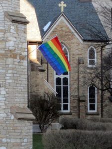 A rainbow flag is flying outside of a church.