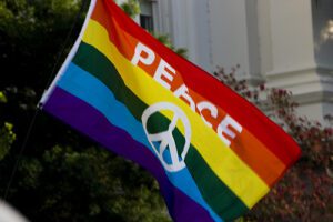 A rainbow flag with a peace symbol on it.