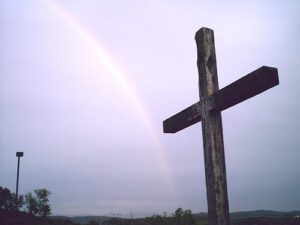 A cross with a rainbow in the background.