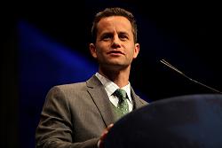 A man in a suit standing at a podium.