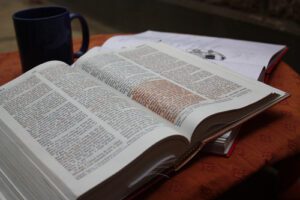 An open book on a table next to a cup of coffee.