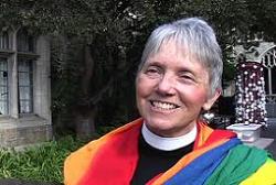 A woman wearing a rainbow flag in front of a church.