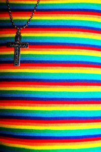 A rainbow striped necklace with a cross on it.