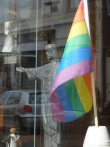 A statue of jesus in front of a rainbow flag.