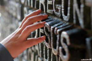 A child's hand reaching for the letters on a wall.