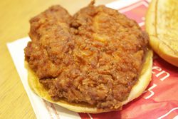 A fried chicken sandwich on a piece of paper.