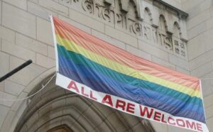 A rainbow flag hangs from the side of a building.