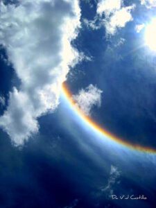 An image of a rainbow in the sky with clouds.