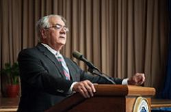 A man in a suit standing at a podium.