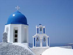 A white church with blue domes and a blue sky.