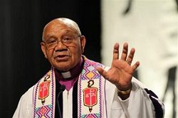 A priest is waving his hand in front of a crowd.