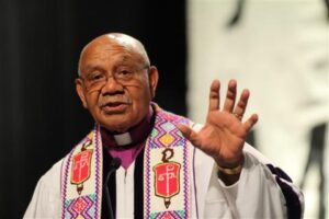 A man in a purple robe is waving his hand.