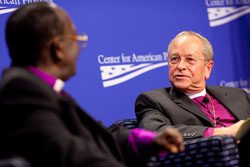 Two men sitting in a chair talking to each other.