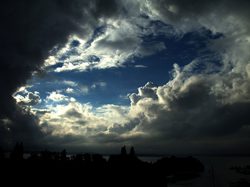 A dark sky with clouds over a lake.