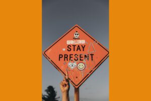 A person holding up a sign that says stay present.