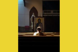 A woman sits in a pew in a church.