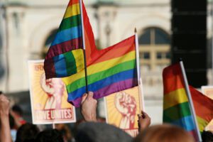 A group of people waving rainbow flags in front of a building.