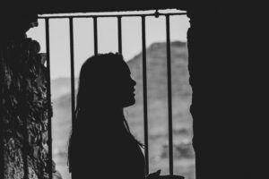 A silhouette of a woman looking out of a window.