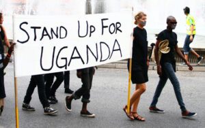 A group of people holding a sign that says stand up for uganda.