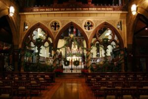 The interior of a church with wooden pews and an ornate ceiling.