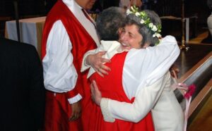 A woman in a red robe is hugging another woman in a red robe.