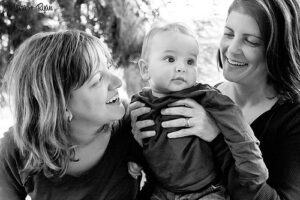 A black and white photo of three women holding a baby.