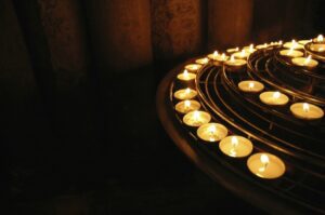 Lit candles on a circular table in a church.