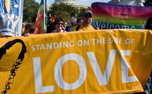 A group of people holding a banner that says standing on the side of love.