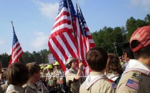 A group of boy scouts holding american flags.