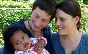 Two women holding a baby in their arms.