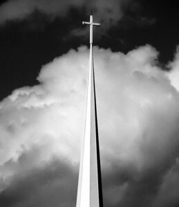 A church steeple with a cross in the sky.