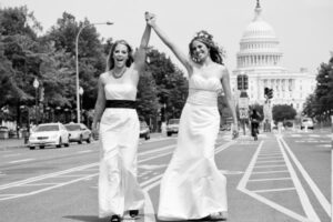 Two brides walking down the street in front of the capitol building.