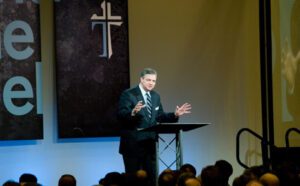 A man standing at a podium in front of an audience.