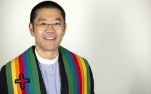 A man with glasses and a rainbow sash.