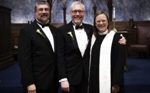 Three people in tuxedos posing for a photo.