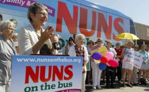 A group of people standing in front of a bus that says nuns on the bus.