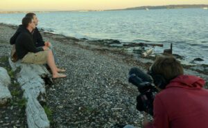 A group of people sitting on a beach with a camera.