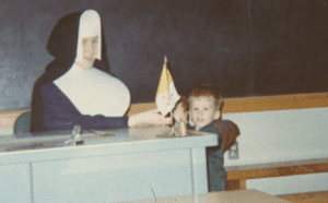 A nun is holding a flag in front of a boy.