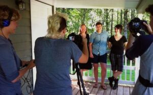 A group of people standing on a porch with cameras.