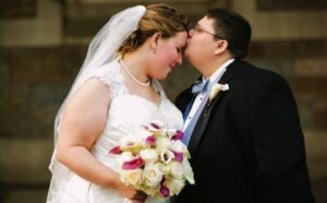 A bride and groom kissing in front of a building.