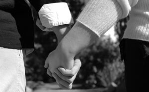 Black and white photo of two people holding hands.