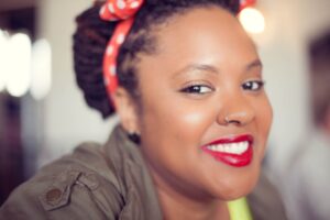 A black woman smiling with a polka dot headband.